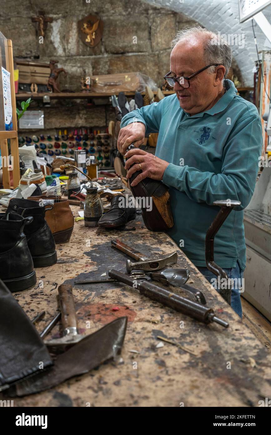 Kleine Schuhmacherwerkstatt. Handwerker wollen ein Paar handgefertigte Schuhe reparieren. Perugia, Umbrien, Italien, Europa Stockfoto