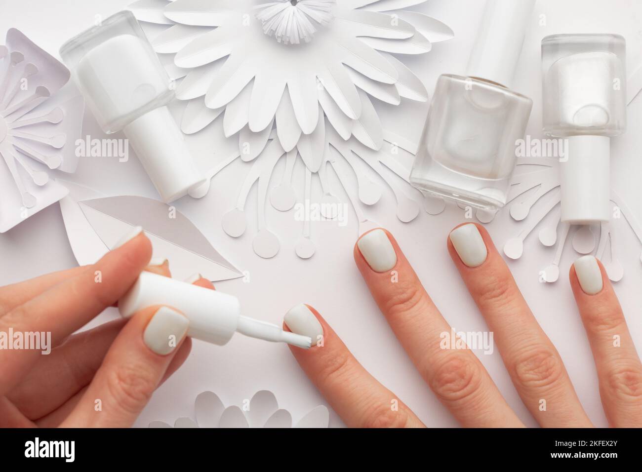 Weißer Nagellack mit weißen Blüten auf dem Tisch. Hochwertige Fotos Stockfoto