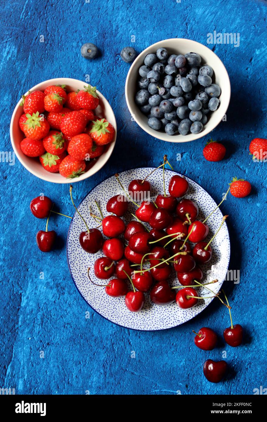 Sommerstille mit frischen Beeren auf Keramikplatten. Foto von oben mit Bio-Kirsche, Heidelbeere und Erdbeere. Konzept der gesunden Ernährung. Stockfoto