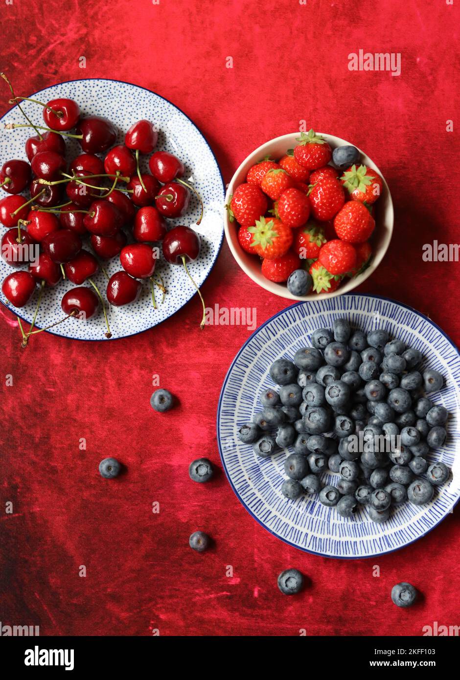 Sommerstille mit frischen Beeren auf Keramikplatten. Foto von oben mit Bio-Kirsche, Heidelbeere und Erdbeere. Konzept der gesunden Ernährung. Stockfoto