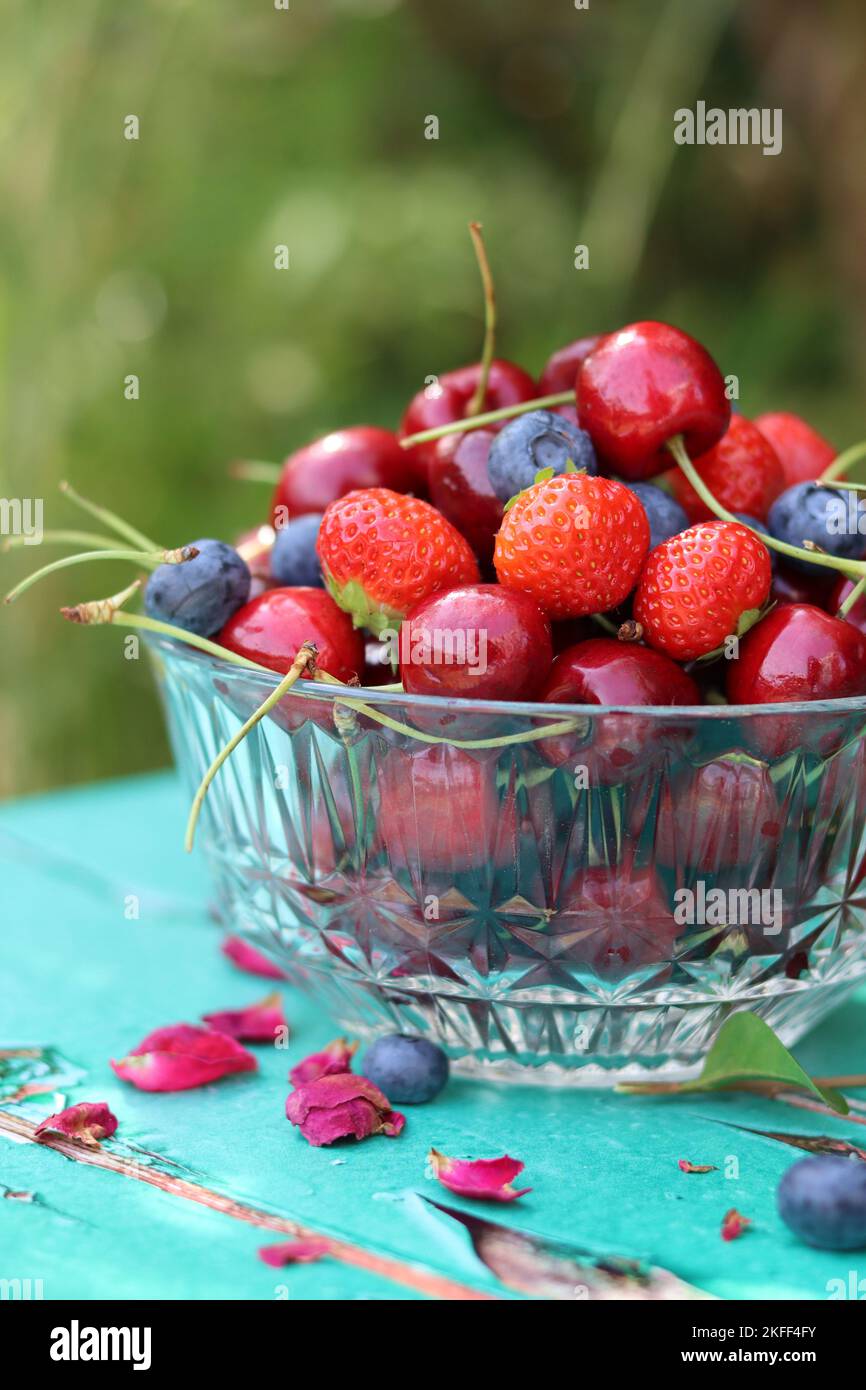 Glasschüssel mit saftigen Bio-Beeren. Sommerstille mit Erdbeere, süßer Kirsche, Blaubeere. Das Konzept des Frischessens. Stockfoto