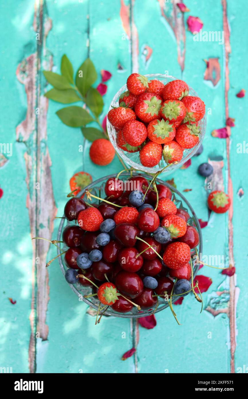 Glasschüssel mit saftigen Bio-Beeren. Sommerstille mit Erdbeere, süßer Kirsche, Blaubeere. Das Konzept des Frischessens. Stockfoto