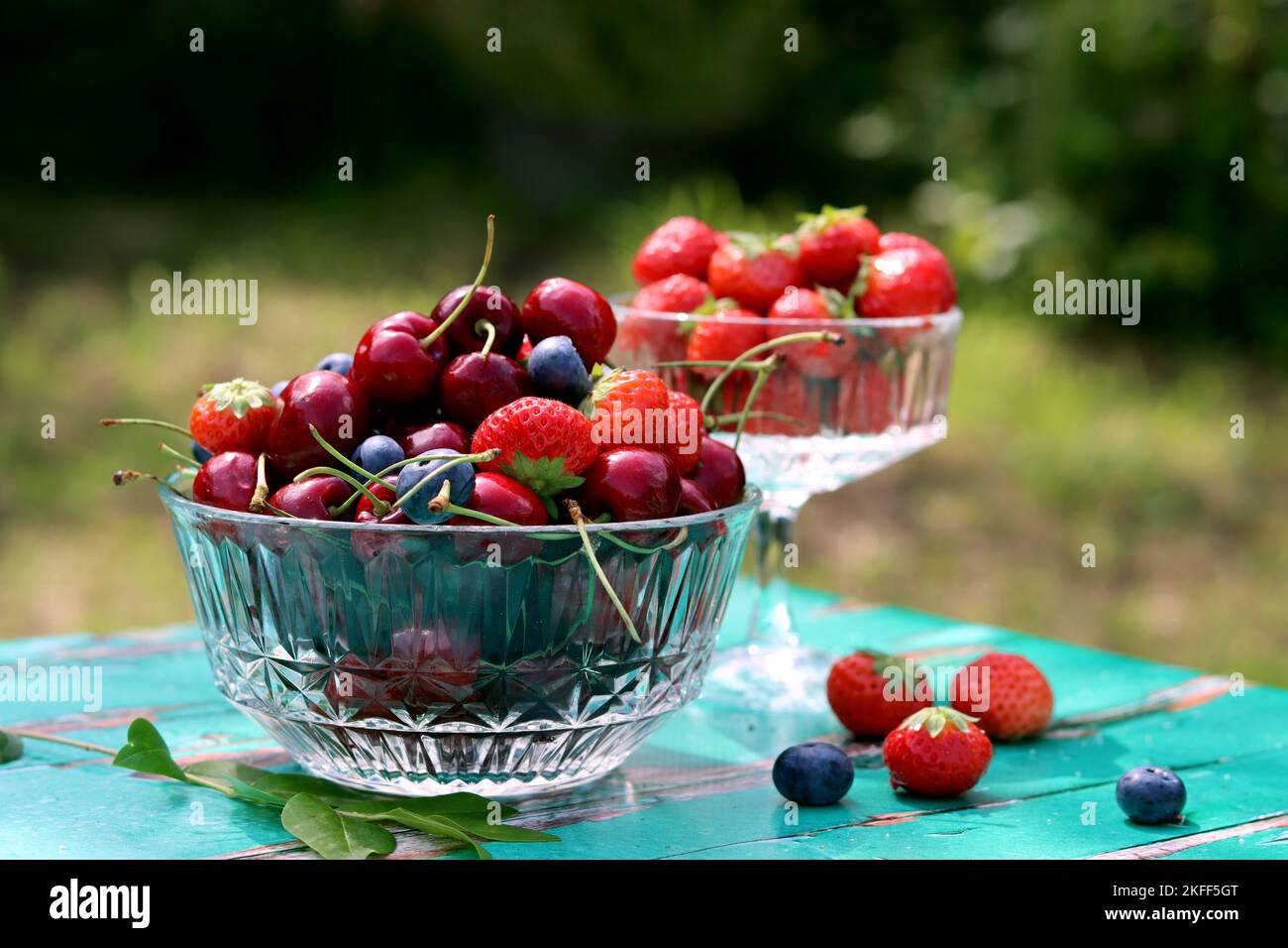 Glasschüssel mit saftigen Bio-Beeren. Sommerstille mit Erdbeere, süßer Kirsche, Blaubeere. Das Konzept des Frischessens. Stockfoto