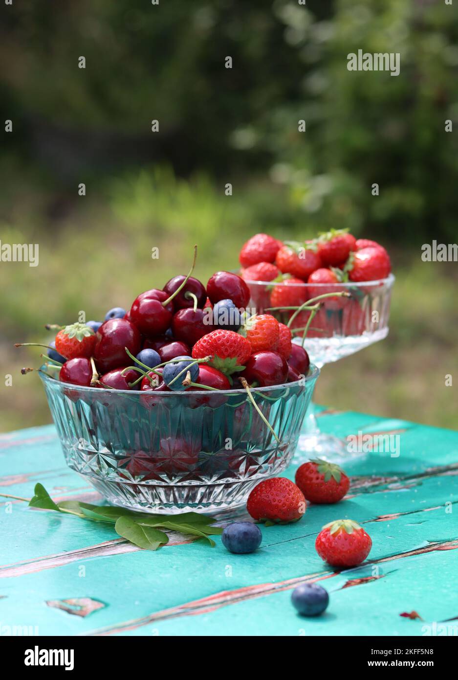 Glasschüssel mit saftigen Bio-Beeren. Sommerstille mit Erdbeere, süßer Kirsche, Blaubeere. Das Konzept des Frischessens. Stockfoto