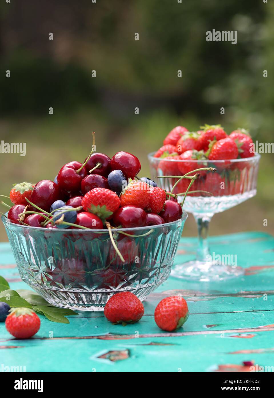 Glasschüssel mit saftigen Bio-Beeren. Sommerstille mit Erdbeere, süßer Kirsche, Blaubeere. Das Konzept des Frischessens. Stockfoto