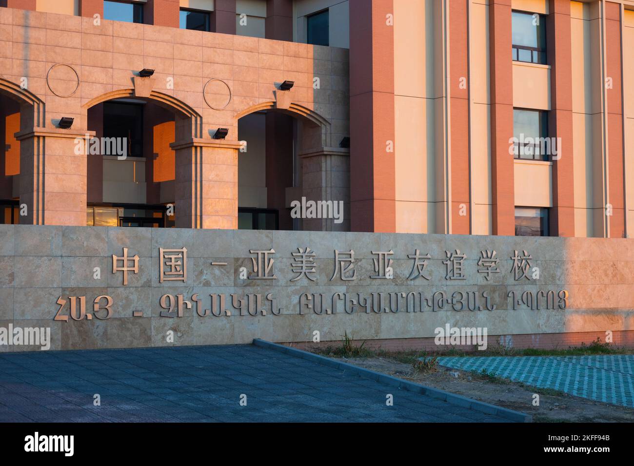 Jerewan, Armenien - 27. Oktober 2022: Armenisch-chinesische Freundschaftsschule, geschrieben an der Wand auf Armenisch und Mandarin. Sonnenlicht gibt den Wänden eine warme Stockfoto