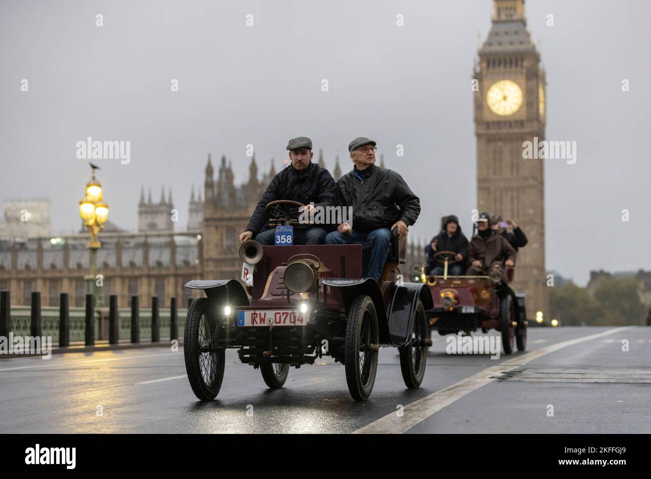 2022 London nach Brighton Veteran Car Run, die weltweit größte Versammlung von Oldtimern, macht sich an einem nassen Wintermorgen über die Westminster Bridge auf den Weg. Stockfoto