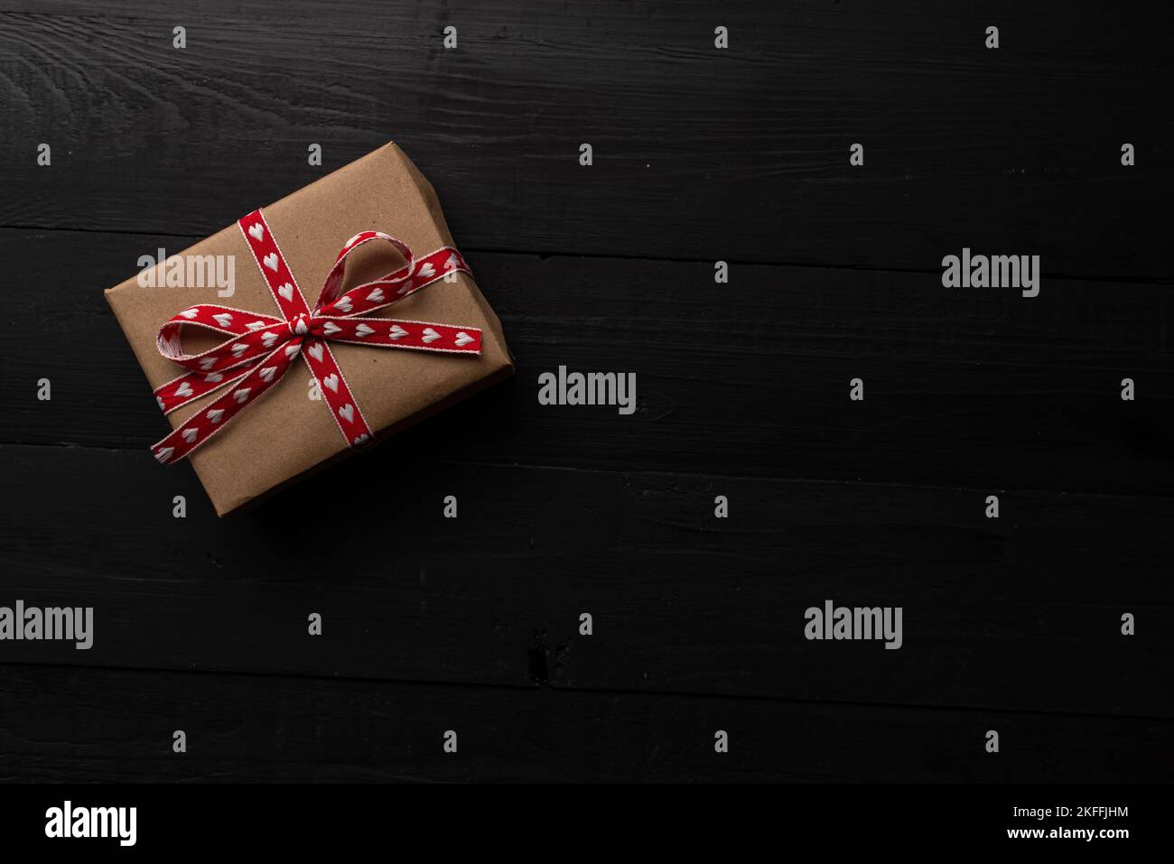 Einzelne Geschenkbox auf schwarzem Holz. Geschenk für valentinstag. Stockfoto