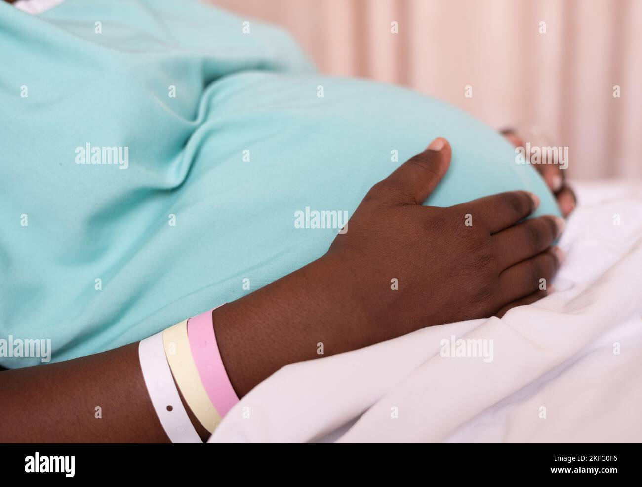 Eine schwangere Frau in den Wehen, die in einem Krankenhausbett liegt und auf die Geburt ihres Babys wartet. Stockfoto