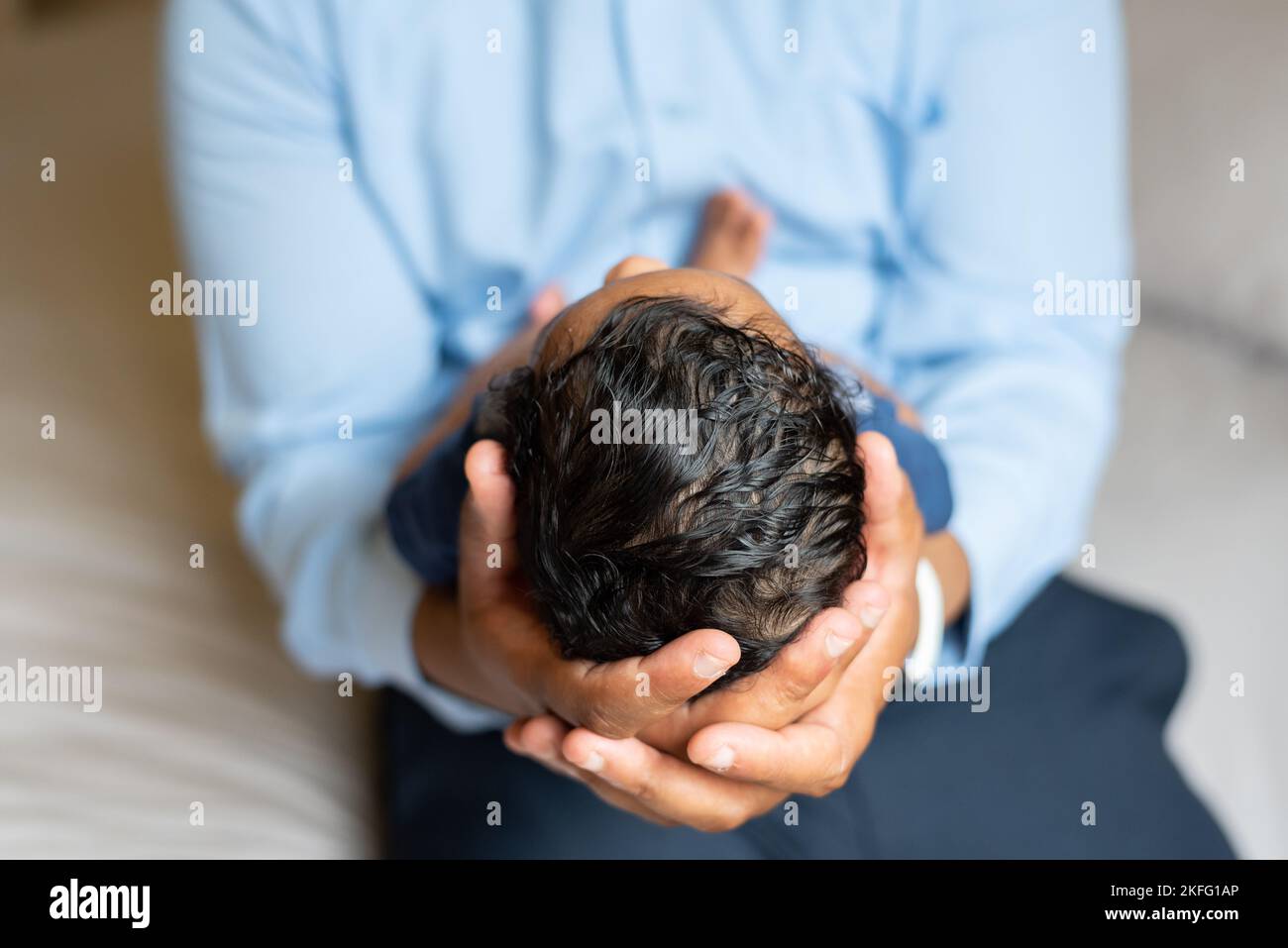 Ein Vater, der sein neugeborenes Baby in den Händen hält, mit einer Nahaufnahme von Kopf und Haar des Babys Stockfoto