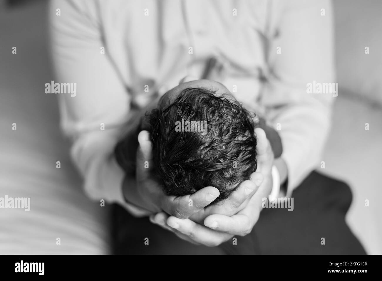 Ein Vater, der sein neugeborenes Baby in den Händen hält, mit einer Nahaufnahme von Kopf und Haar des Babys Stockfoto