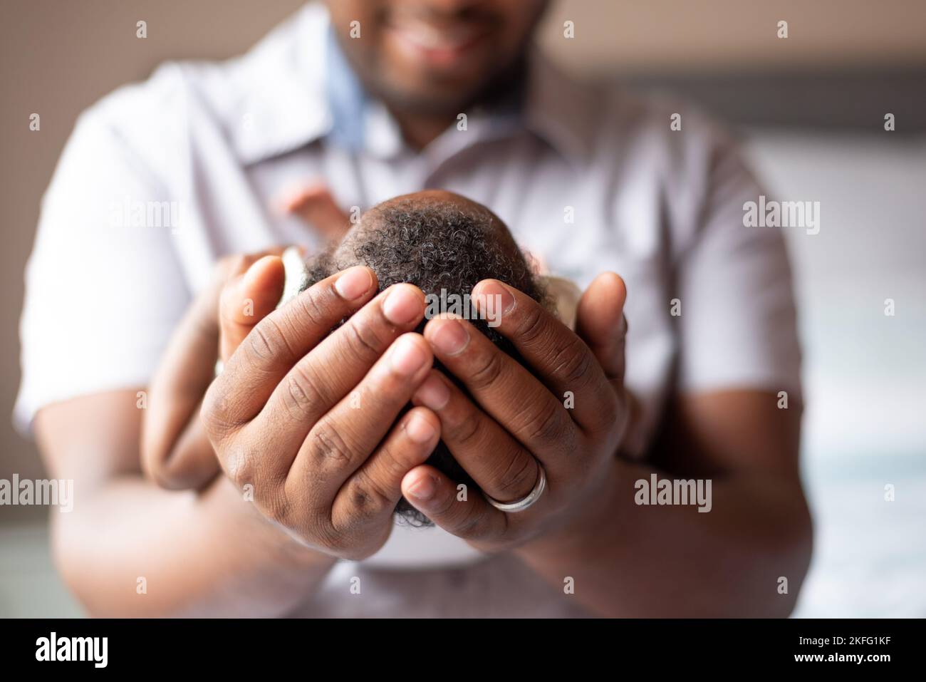 Ein Vater, der sein neugeborenes Baby in den Händen hält, mit einer Nahaufnahme von Kopf und Haar des Babys Stockfoto