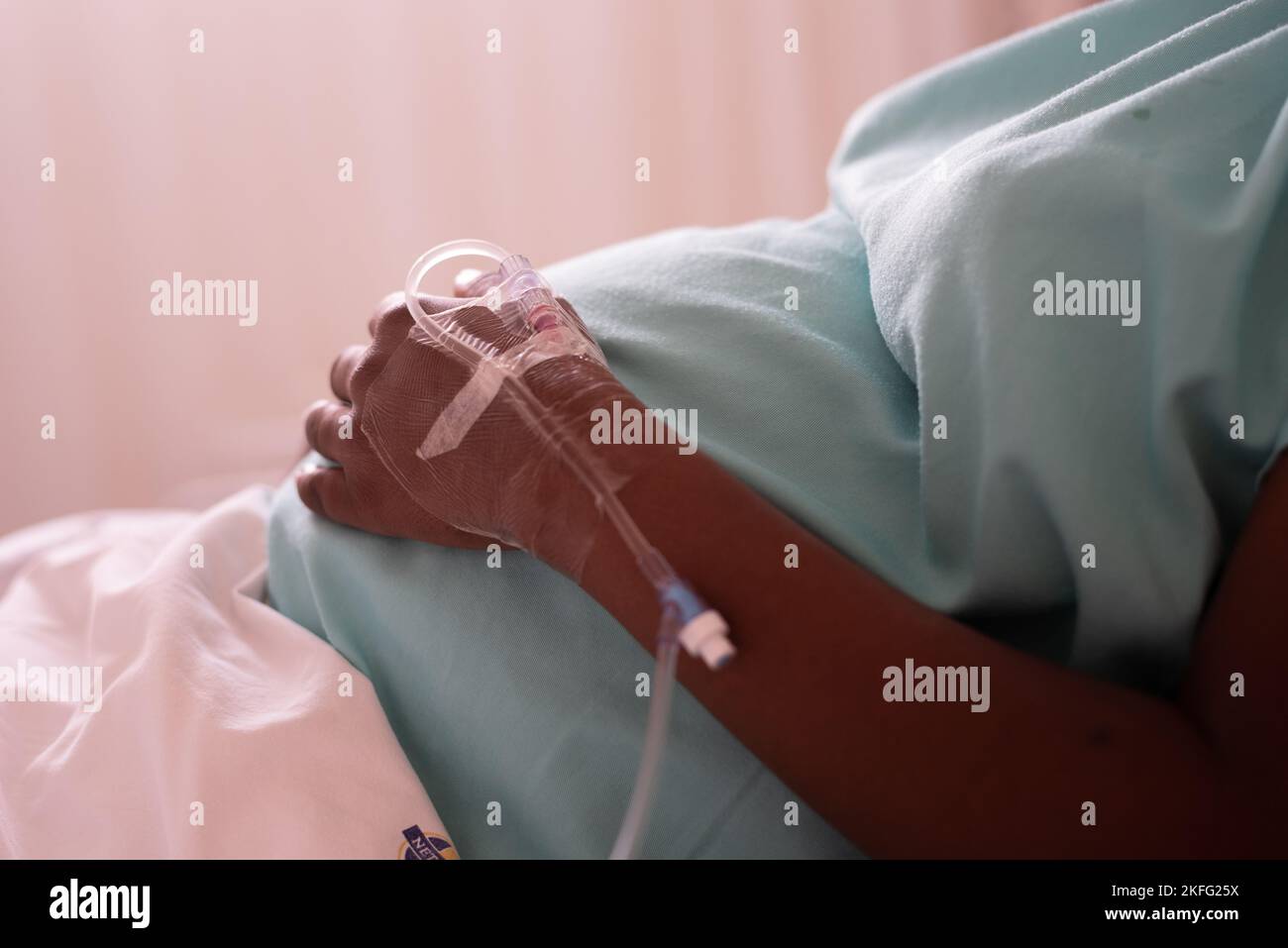 Eine schwangere Frau in den Wehen, die in einem Krankenhausbett liegt und auf die Geburt ihres Babys wartet. Stockfoto