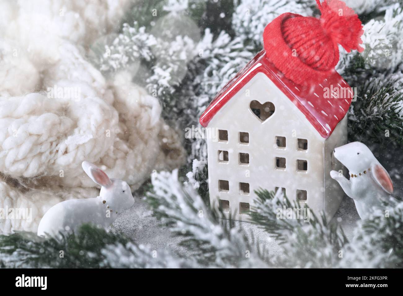 Neujahrskarte. Weihnachten. Zwei Häuser in weißem Schal mit Christbaumzweigen im Schnee, lustigen Hasen und schönem Bokeh gewickelt. Neue Jahre Stockfoto