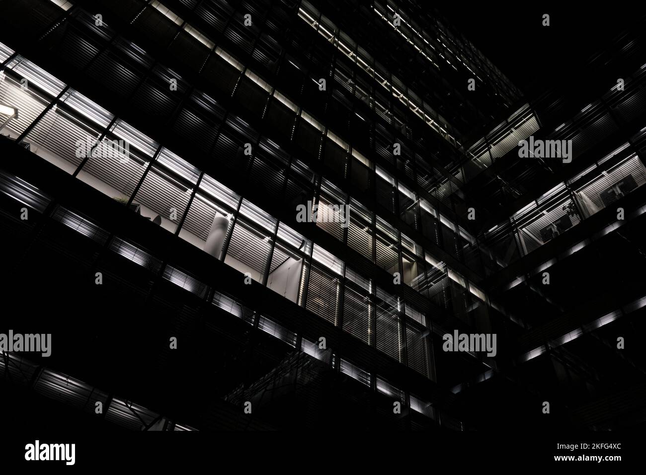 Eine dunkle Nacht in Berlin - Berliner Nachtarchitektur. Modernes Architekturgebäude, Bürogebäude mit Lichtern in den Fenstern. Stockfoto