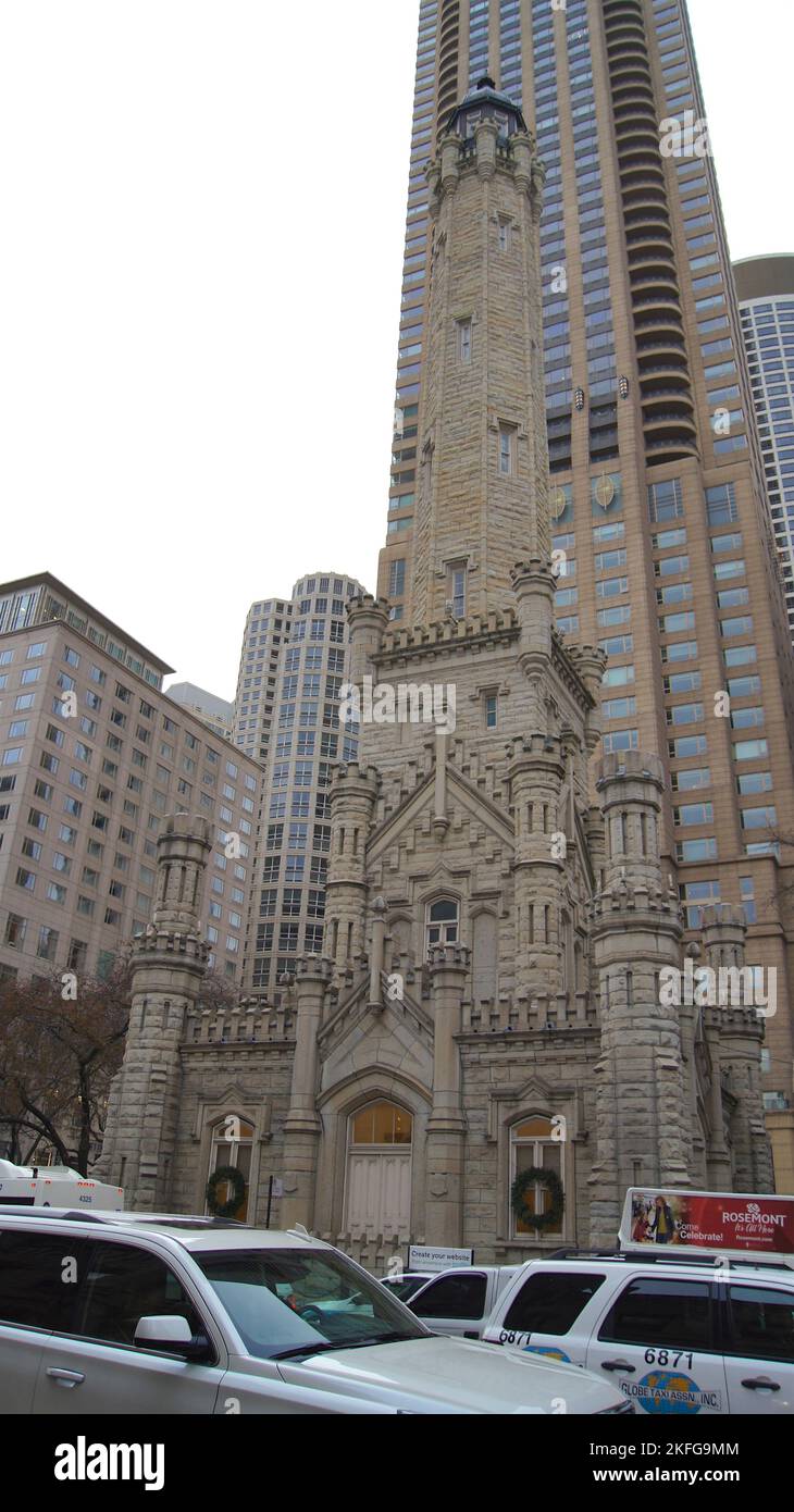 CHICAGO, ILLINOIS, USA - 11. Dez 2015: Außenansicht des historischen Wasserturms mit weißem Auto im Vordergrund und Wolkenkratzer im Hintergrund Stockfoto