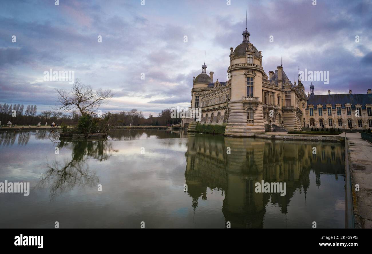 Domaine de Chantilly, Schloss Chantilly bei Sonnenuntergang, Spiegelung des Wolkenhimmels im Teich. Berühmtes Touristenziel in der Nähe von Paris. Stockfoto