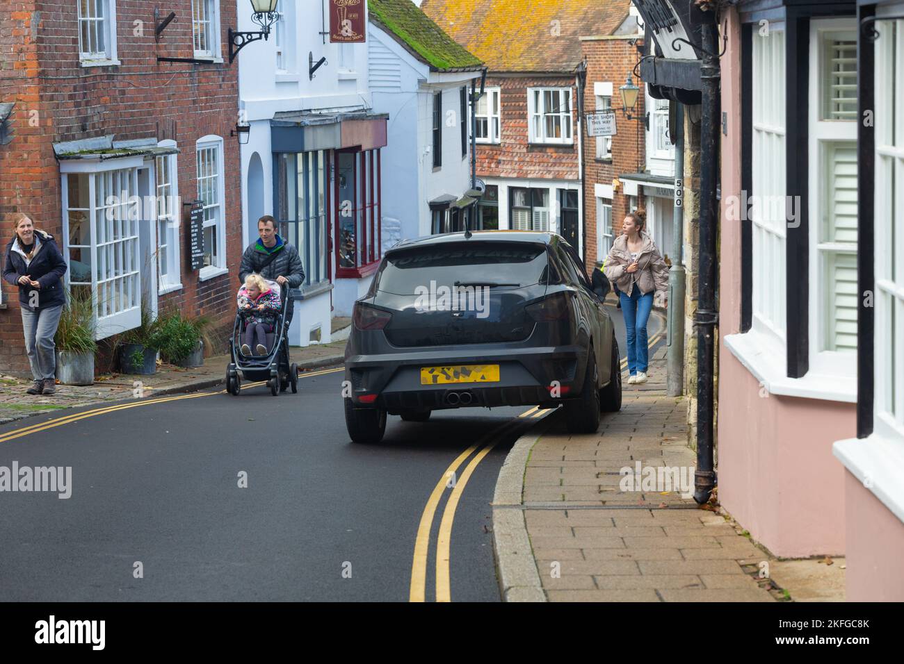 Rücksichtsloses Parken von Fahrern auf zweifachen gelben Linien und auf dem Bürgersteig sowie Fußgängern mit Kinderwagen auf der Straße, Rye, East Sussex, großbritannien Stockfoto