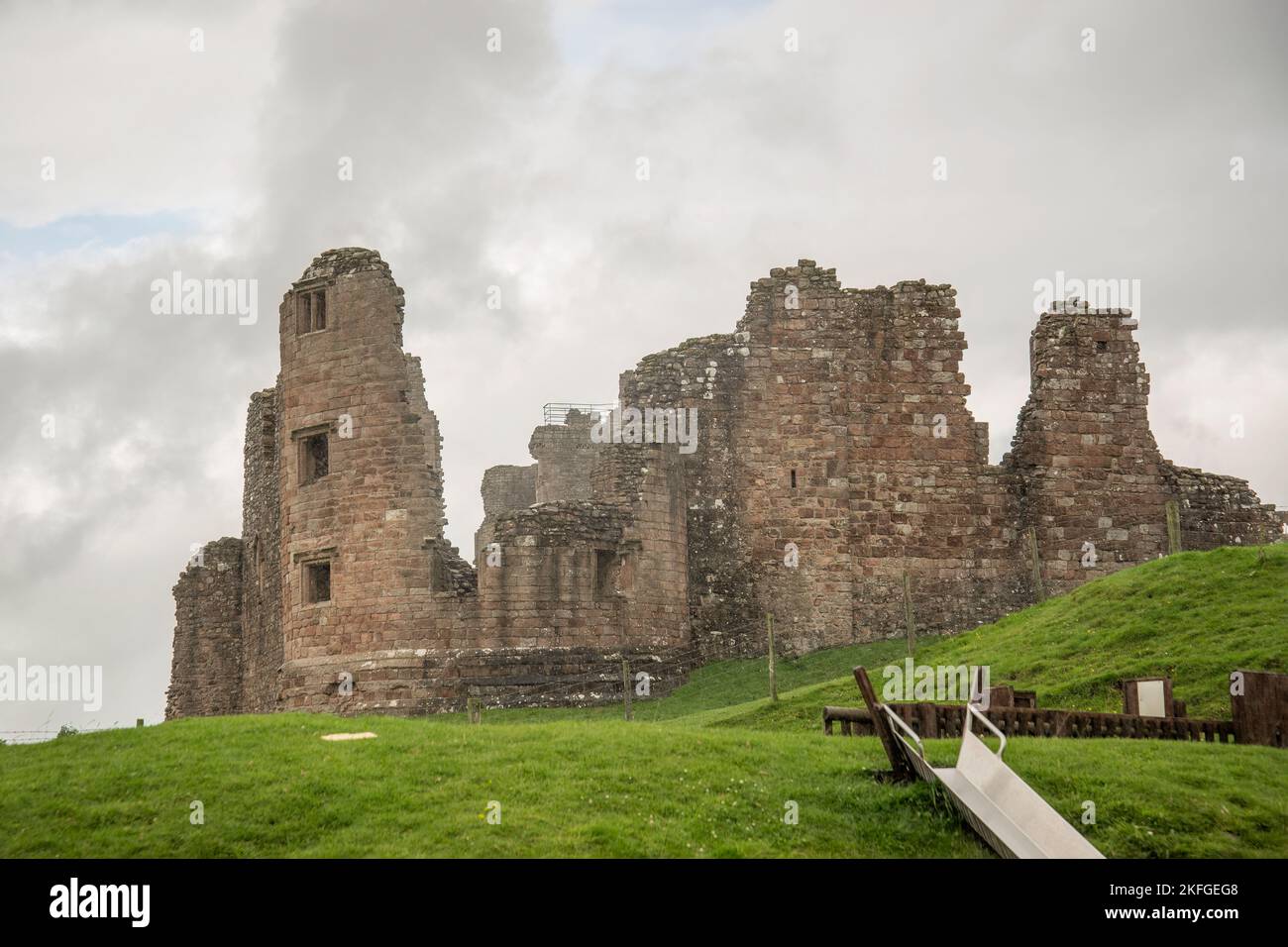 Ruinen von Brough Castle, mit Kinderrutsche im Vordergrund und grünem Gras Stockfoto