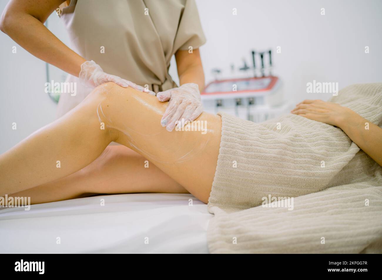 Crop Masseuse Anwendung Creme auf Bein der Frau Stockfoto