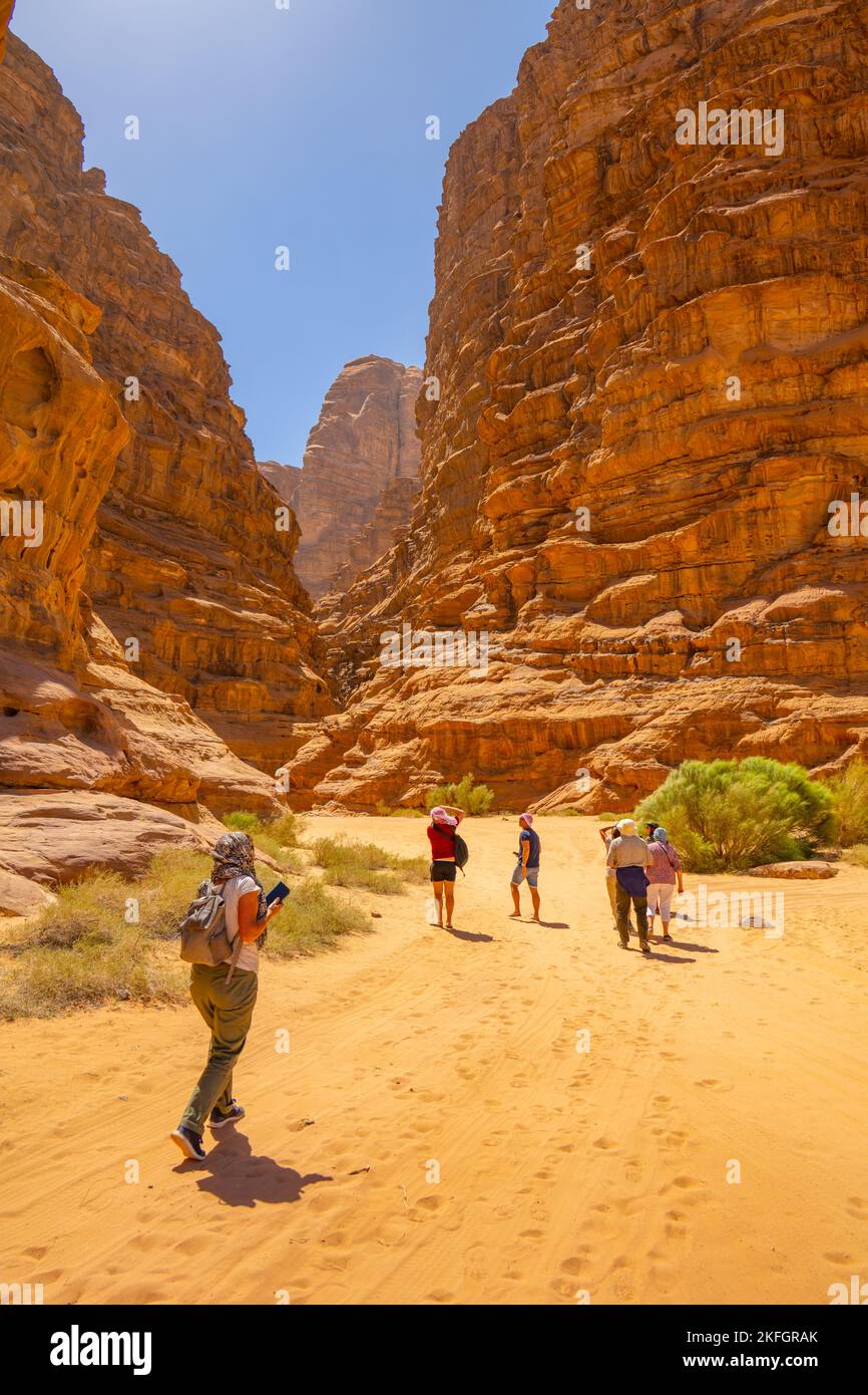 Touristen, die in einen Canyon im Wadi Rum Jordan wandern Stockfoto