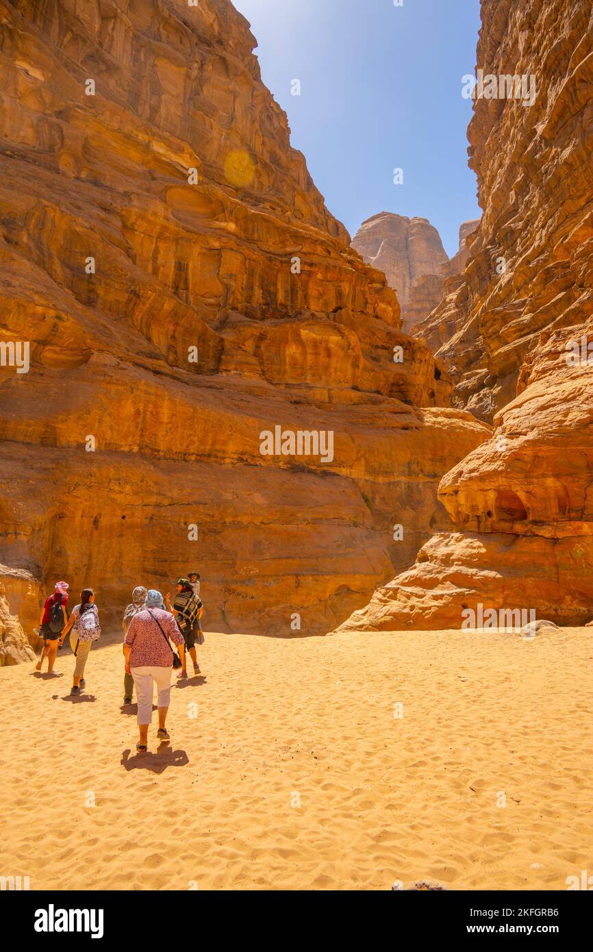 Touristen, die in einen Canyon im Wadi Rum Jordan wandern Stockfoto