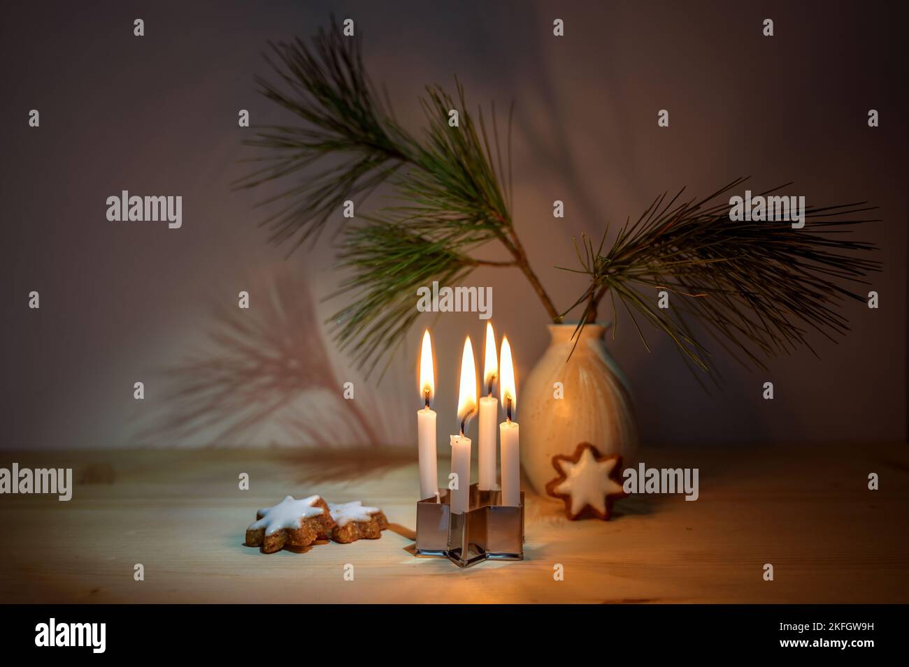Kleine Adventskerzen auf einem Keksschneider platziert, Zimt-Stern-Kekse ein Kiefernzweig in einer Vase auf einem Holztisch, winzig Dekoration in der Weihnachtsmeere Stockfoto