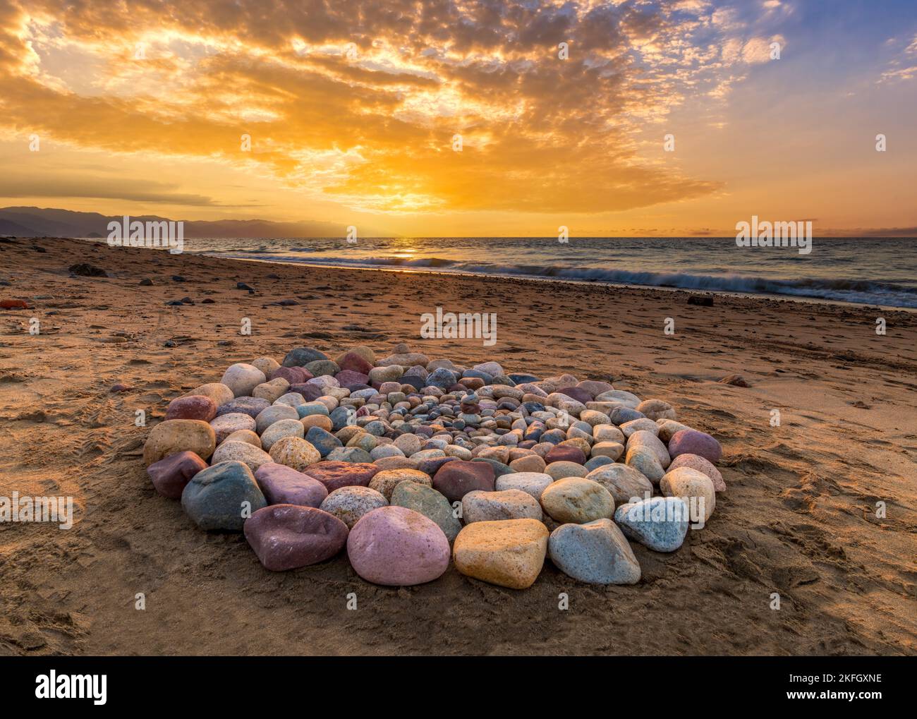 Während des Sonnenuntergangs am Strand werden rituelle Steine für spirituelle Zeremonien in Einem Kreis angeordnet Stockfoto