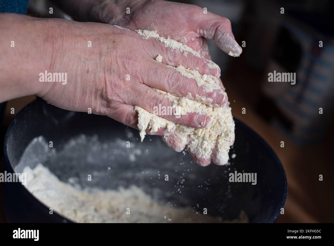 Die Hände reiben Mehl in eine Rührschüssel. Backen und Backen von Scones zu Hause. Stockfoto