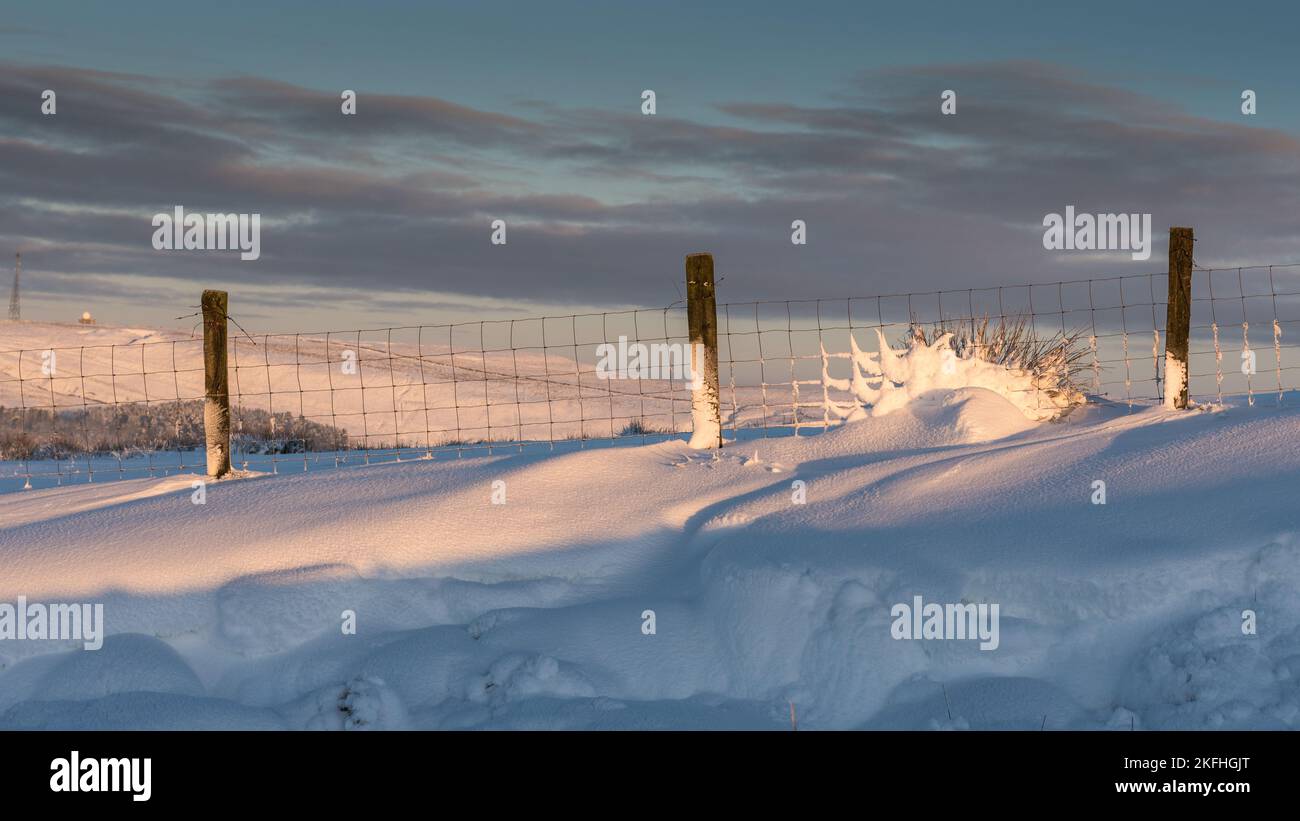 Muster eines Schneesterns im Zaunpfahl. Moody Wolken am Himmel mit Hügeln im Hintergrund. Stockfoto