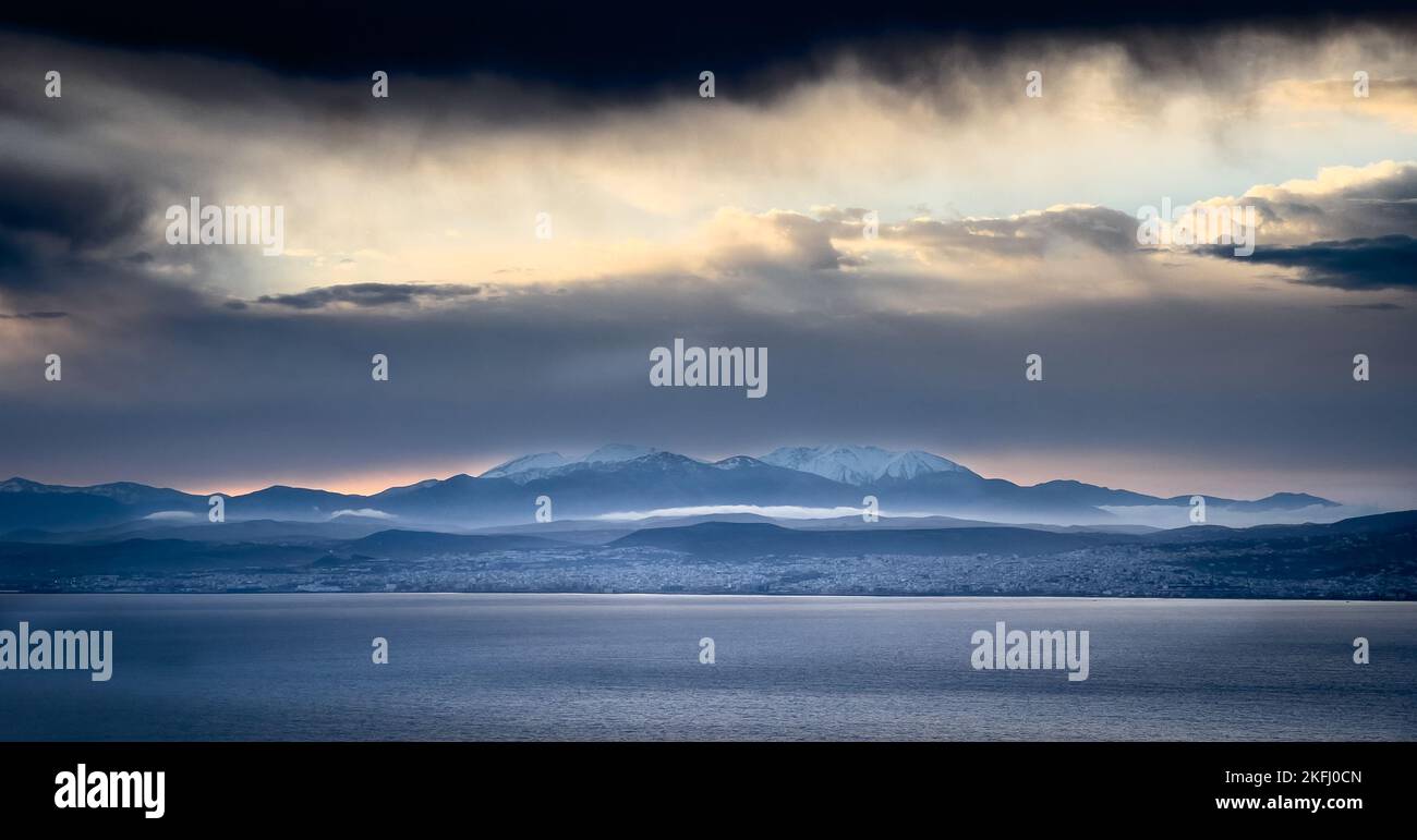 Majestätischer Blick auf die Meereslandschaft und die schneebedeckte Bergkette gegen die Wolkenlandschaft während des Sonnenuntergangs Stockfoto