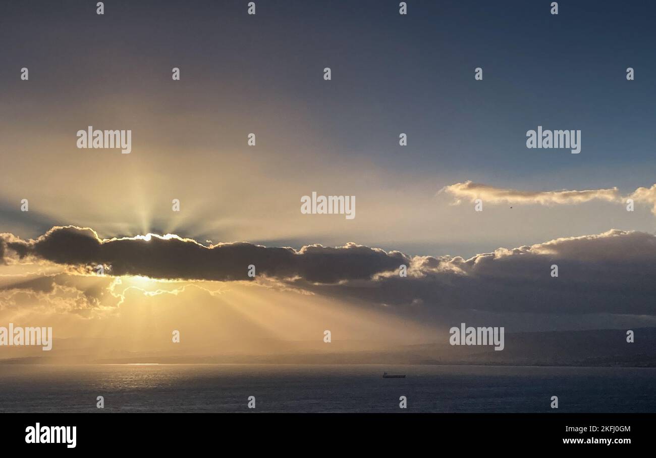 Panoramablick auf das Sonnenlicht, das während des Sonnenaufgangs durch die Wolken auf der Meereslandschaft strömt Stockfoto