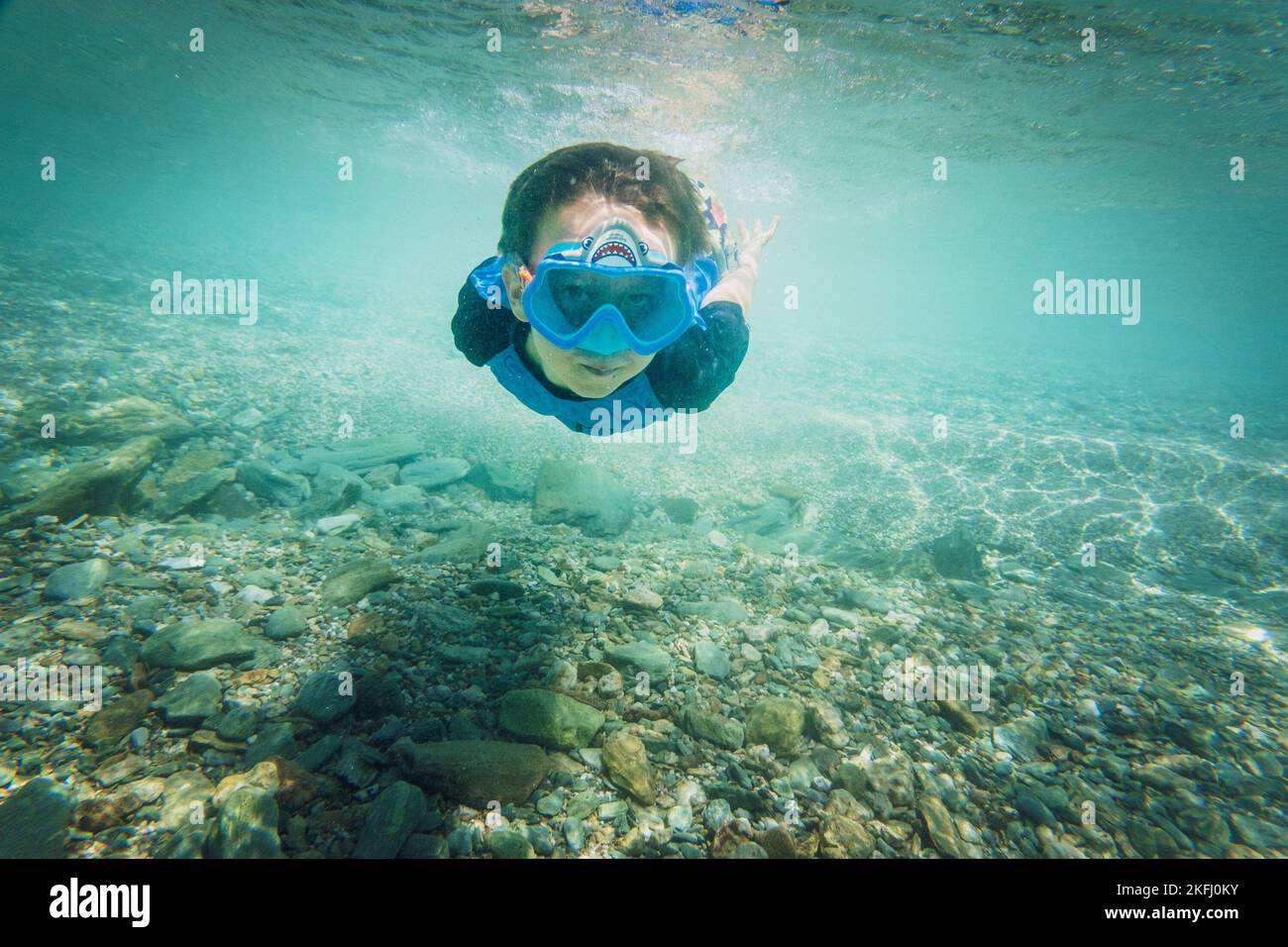 Porträt eines sorglosen Jungen mit blauer Schwimmbrille und Tauchen unter Wasser über dem Meeresboden im Meer Stockfoto