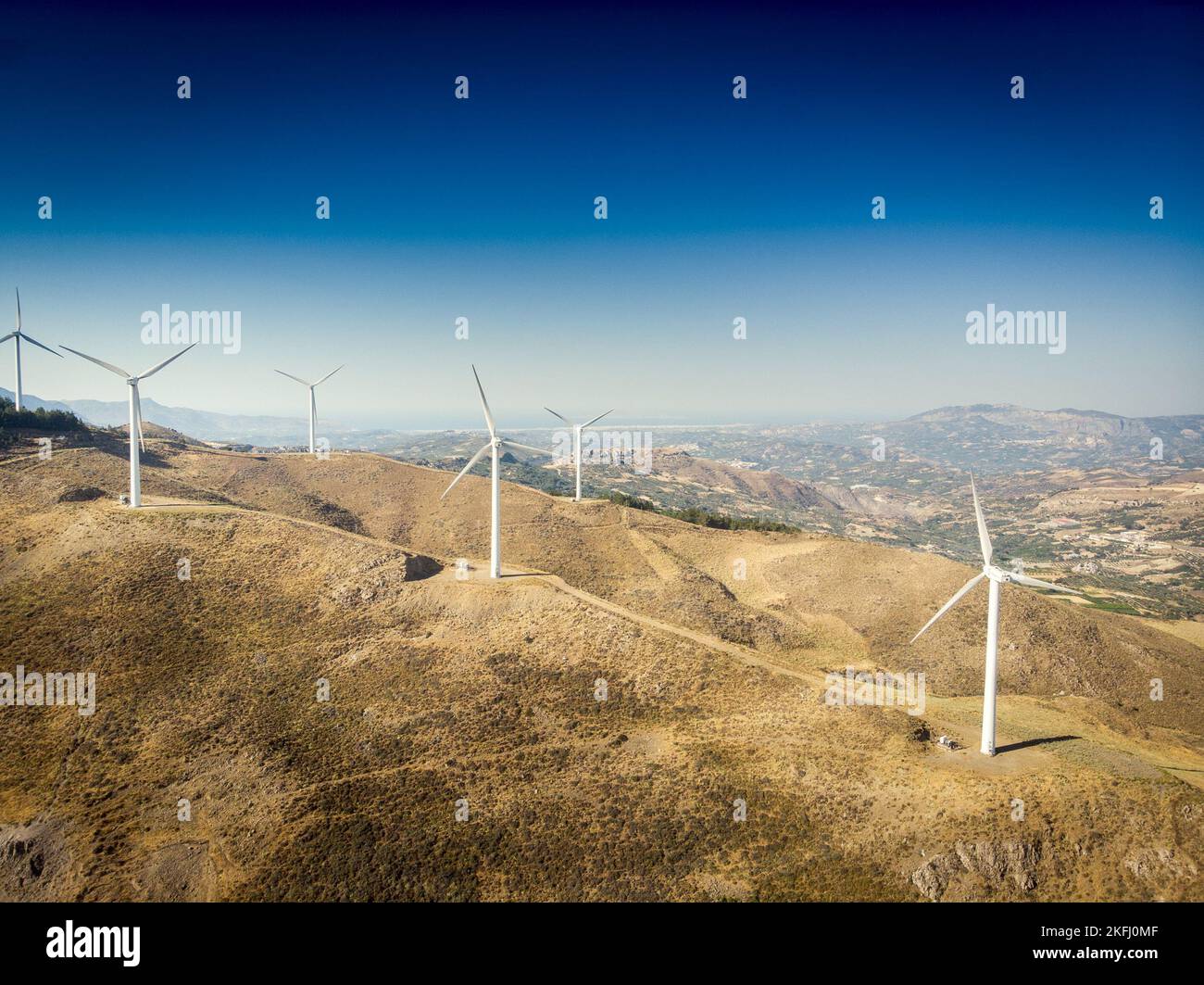 Luftaufnahme von Windkraftanlagen auf den Bergen und majestätische Landschaft gegen blauen Himmel an sonnigen Tagen Stockfoto
