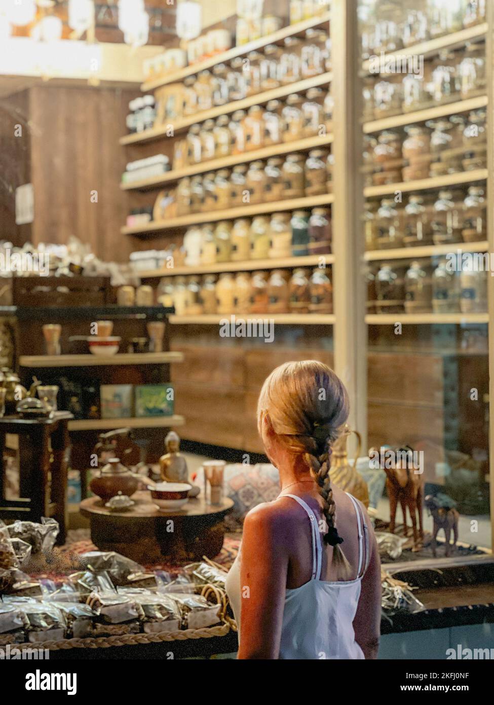 Rückansicht einer Frau mittleren Erwachsenen mit blondem geflochtenem Haar, die Figuren zum Verkauf im Geschäft ansieht Stockfoto