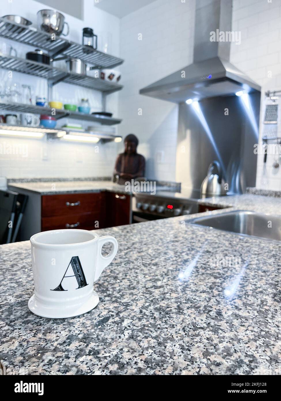 Nahaufnahme des Briefes Eine Tasse mit weißem Kaffee befindet sich auf der Kücheninsel zu Hause Stockfoto