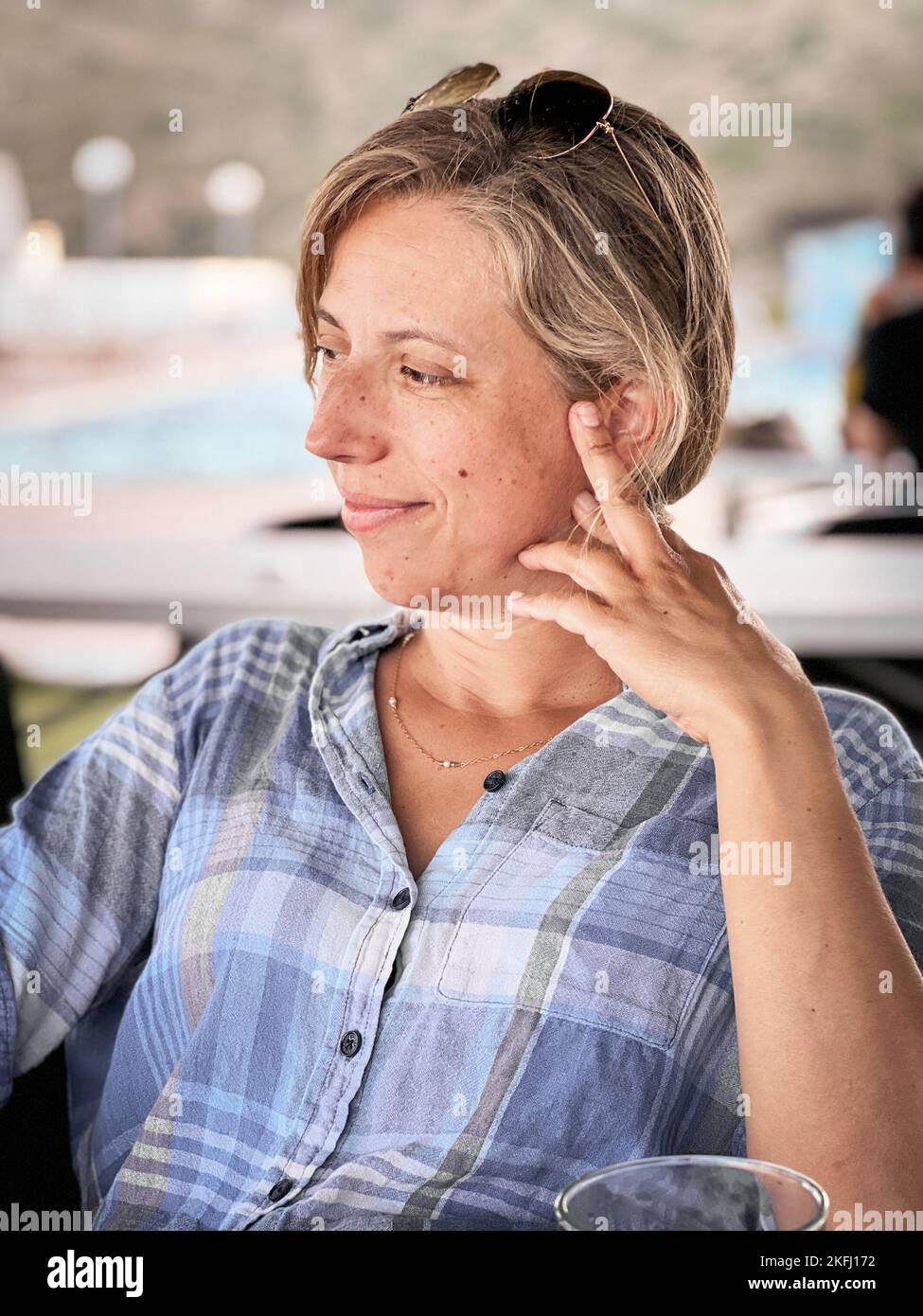 Eine nachdenkliche, schöne lächelnde Frau mit blonden Haaren, die am Wochenende im Restaurant sitzen und wegschauen Stockfoto