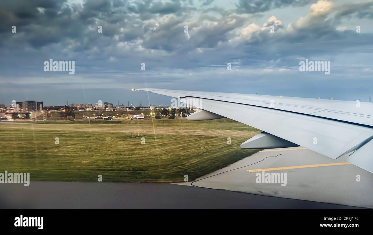 Zugeschnittenes Bild des Flugzeugflügels aus dem Fenster am Flughafen mit bewölktem Himmel im Hintergrund Stockfoto