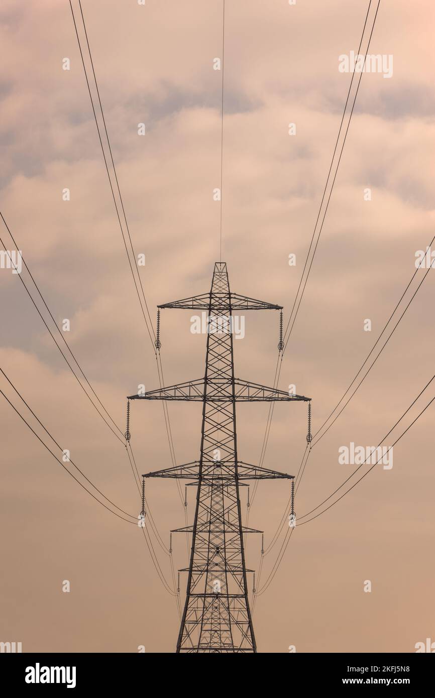 Symmetrische Muster auf dem Strompylon. Bewölkter blau-weißer Himmel. Schleppdrähte und hervorragende Bautechnik. Stockfoto