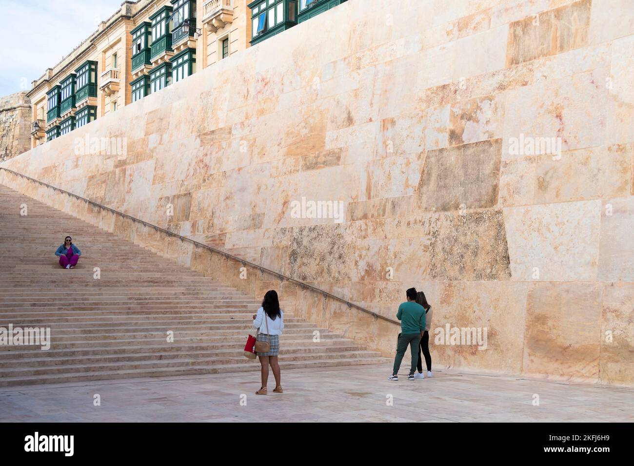 Valletta, Malta - 12. November 2022: Riesige Steinmauer und Treppen im Rahmen des Renzo Piano-Wiederaufbauprojekts und traditioneller Valletta-Holzbalkon Stockfoto