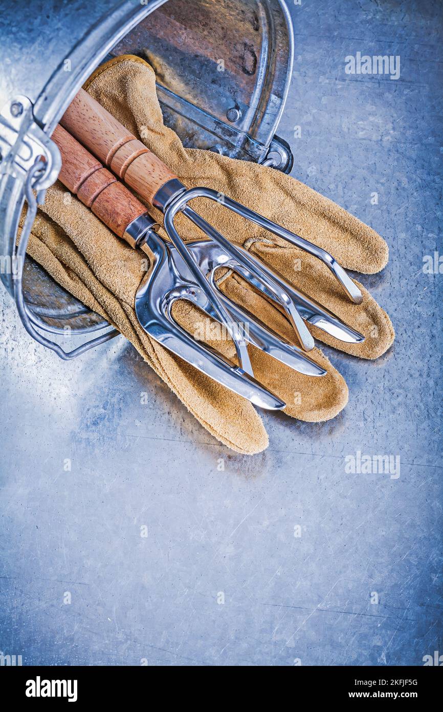 Metall Eimer Hand Rechen Kelle Gabel Leder Sicherheitshandschuhe auf metallischen Hintergrund Gartenkonzept. Stockfoto