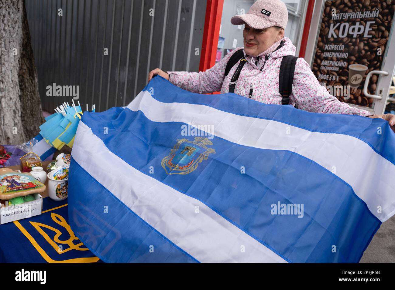 Cherson, Ukraine. 17.. November 2022. Ein Ladenbesitzer wird mit der Stadtflagge von Cherson gesehen. Die Bewohner von Kherson sind immer noch überglücklich über die Befreiung der Stadt und setzen mehr als 8 Monate der Besetzung zu Ende. Dennoch verfügt die südliche regionale Hauptstadt noch immer über keinen Strom, kein Wasser und ein Minimum an Signal- und Nahrungsmittelversorgung. Kredit: SOPA Images Limited/Alamy Live Nachrichten Stockfoto