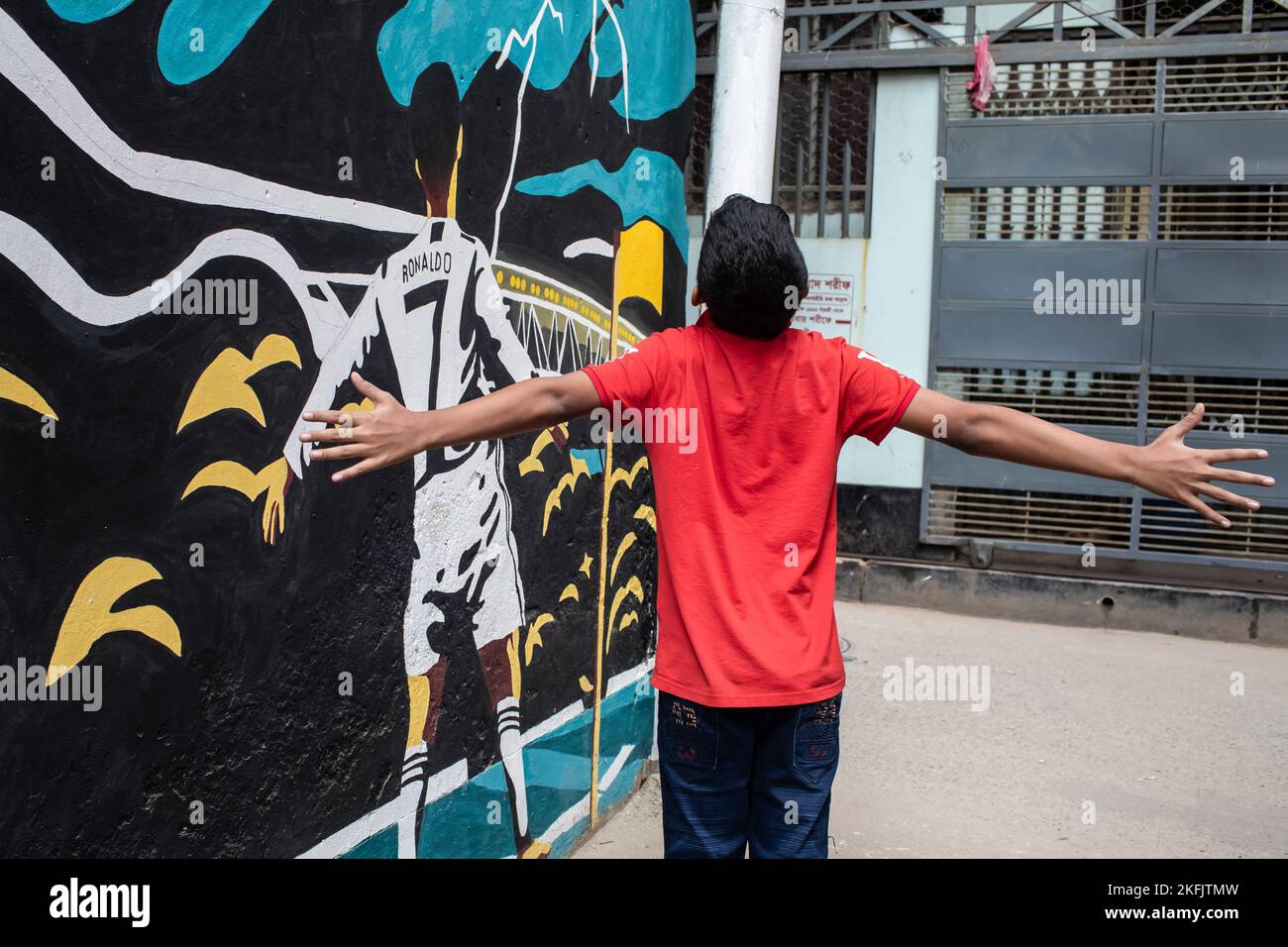 Dhaka, Bangladesch. 17.. November 2022. Ein Junge posiert vor einem Graffiti des berühmten Fußballspielers Cristiano Ronaldo an einer Wand in einer Gasse in Dhaka. Kredit: SOPA Images Limited/Alamy Live Nachrichten Stockfoto