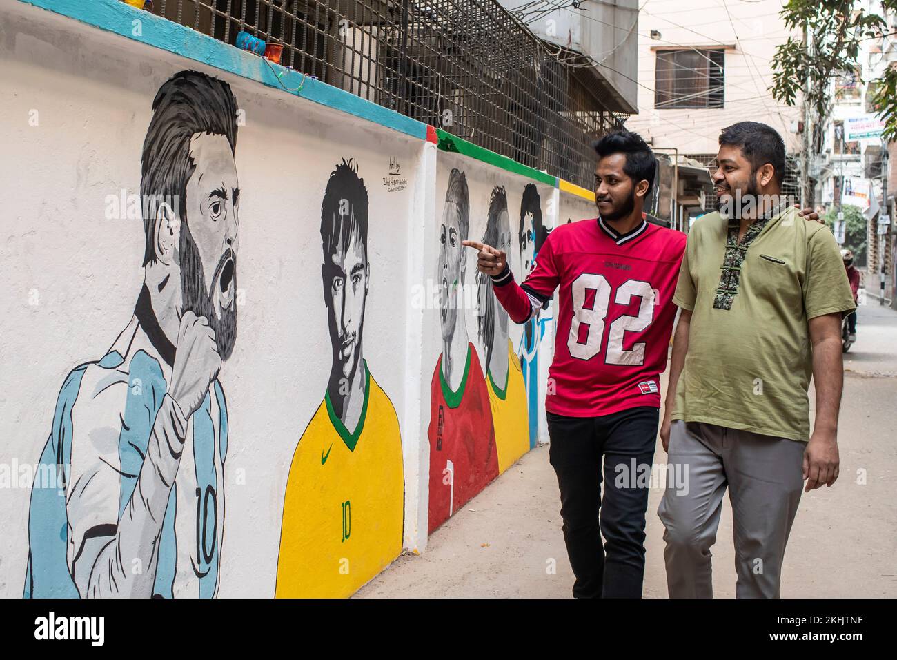 Dhaka, Bangladesch. 17.. November 2022. Männer betrachten Graffiti, die die Fußballstars Lionel Messi, Neymar, Cristiano Ronaldo, Ronaldinho und Diego Maradona vor der FIFA-Weltmeisterschaft 2022 an einer Wand im KM das Lane in Dhaka feiern. Kredit: SOPA Images Limited/Alamy Live Nachrichten Stockfoto