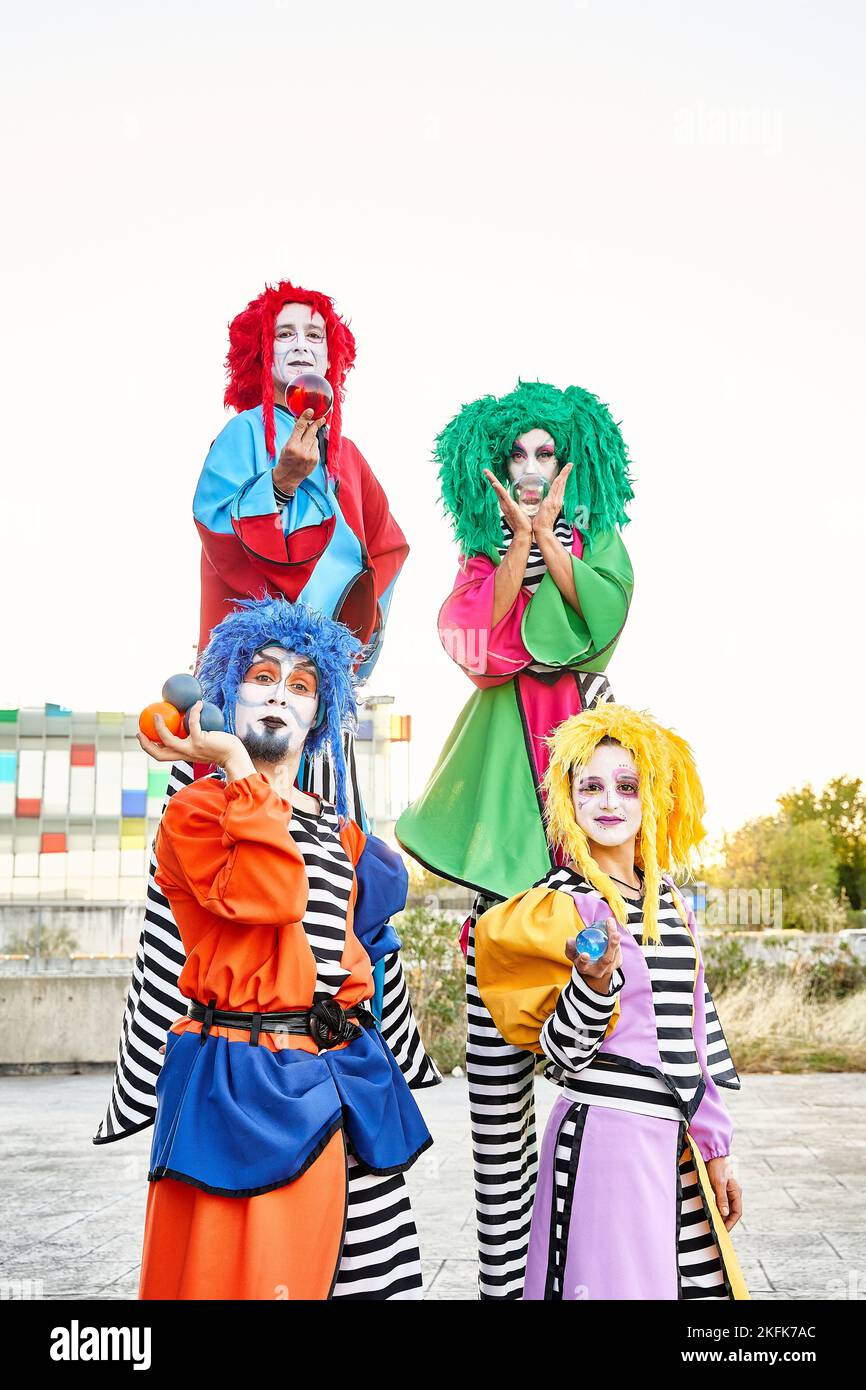 Männliche und weibliche Clowns in farbenfrohen Kostümen und Perücken, die auf die Kamera blicken, die Kristallkugeln in den Händen hält. Stockfoto