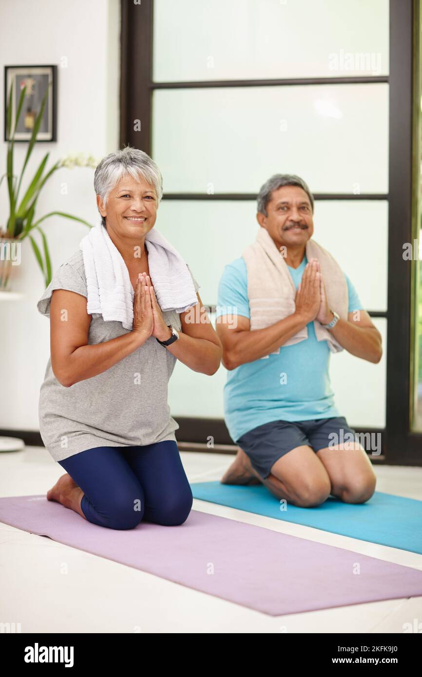 Gut für Körper und Geist. Porträt eines reifen Paares, das zu Hause gemeinsam Yoga macht. Stockfoto