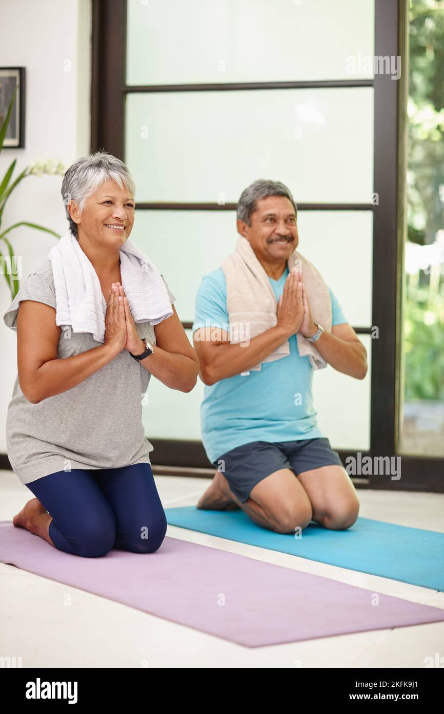 Friedlich und konzentriert. Porträt eines reifen Paares, das zu Hause gemeinsam Yoga macht. Stockfoto
