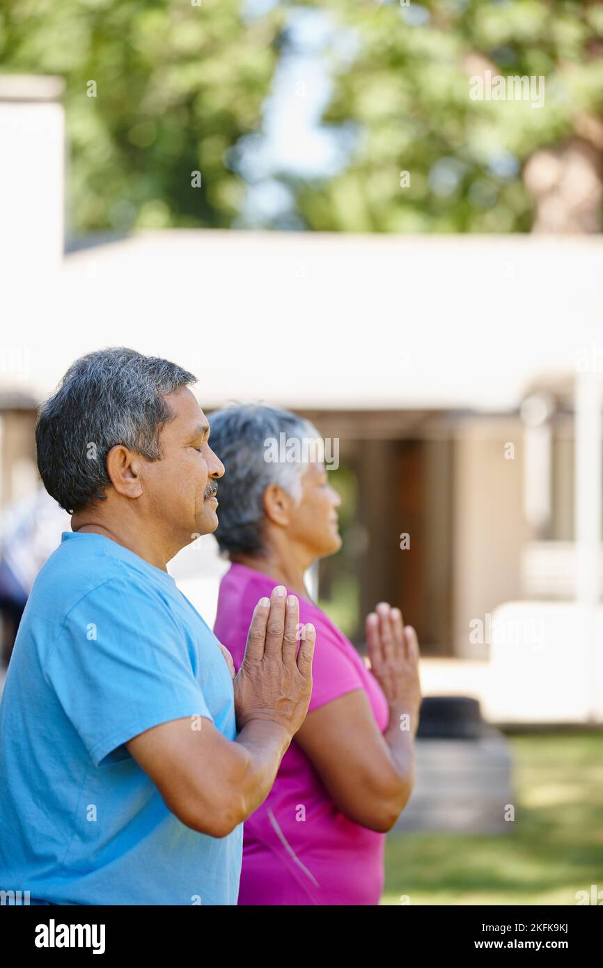 Namaste. Porträt eines reifen Paares, das gemeinsam Yoga in ihrem Hinterhof macht. Stockfoto