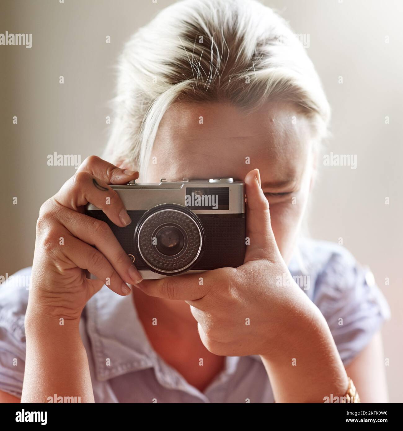 Leben festhalten. Nahaufnahme einer jungen Frau, die mit einer altmodischen Kamera ein Foto gemacht hat. Stockfoto