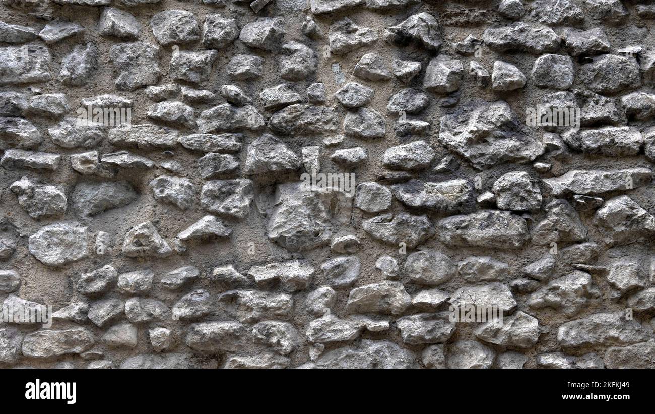 HINTERGRUNDTEXTUR - Wand aus unregelmäßig geformten dunklen Steinen Stockfoto